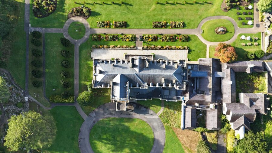 aerial image, taken by a drone, of a roof and the gardens of a stately home.