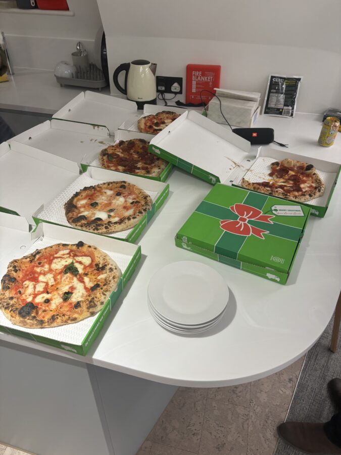 Image showing a selection of Pizzas in takeaway boxes in the kitchen of an office. 